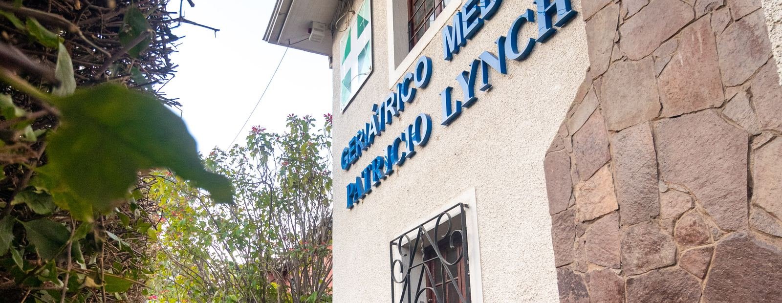 Fachada de la residencia con revestimiento de piedra y el letrero institucional.