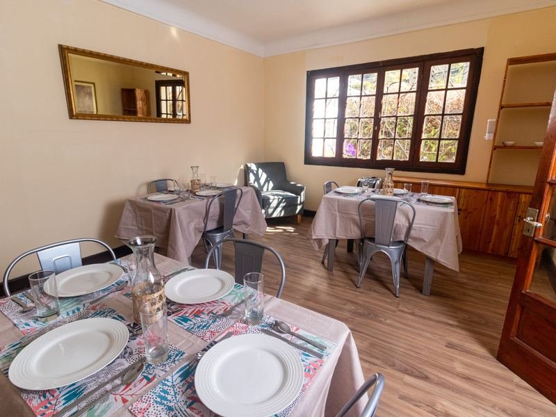 Comedor junto al ventanal, con mesas preparadas.
