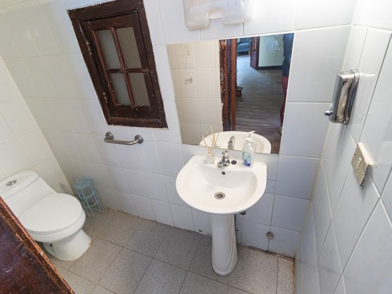 Baño adaptado con barras de apoyo junto al inodoro.