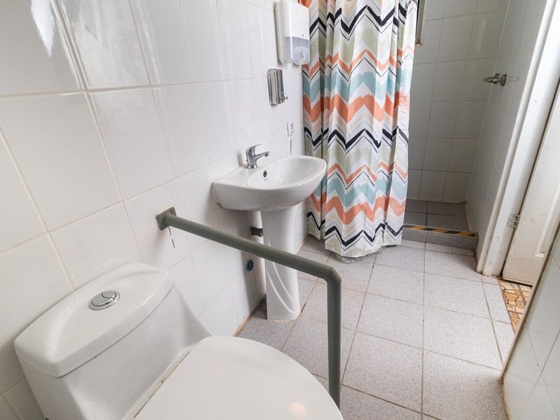Baño adaptado con ducha y barras de apoyo.