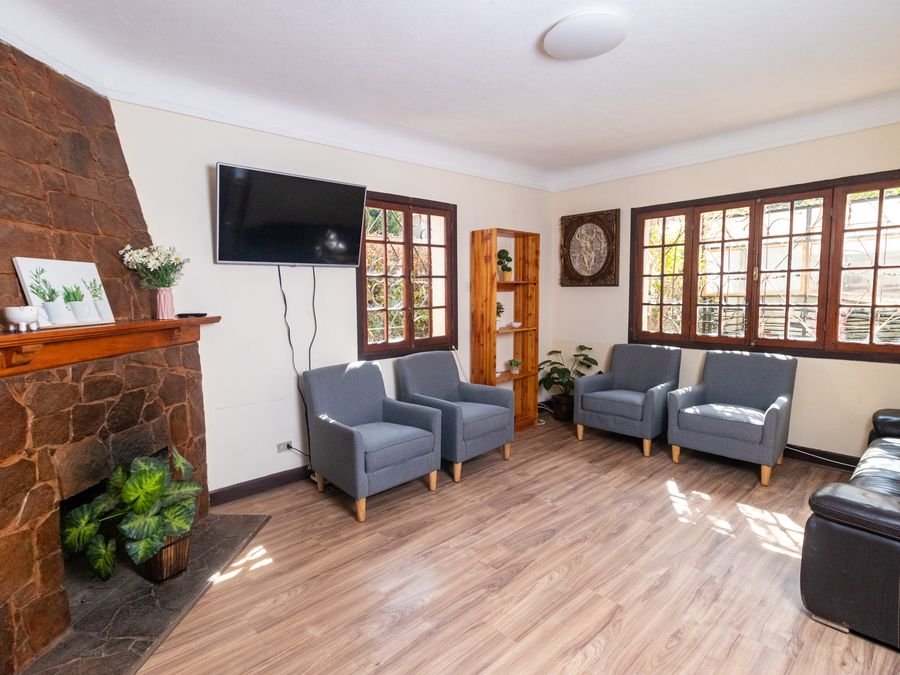Sala de estar con chimenea de piedra, sillones y ventanales al jardín.